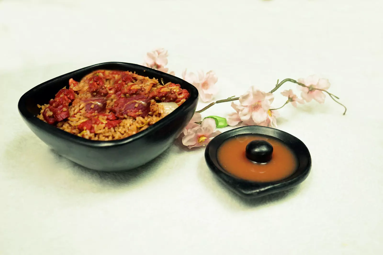 Arroz carbonara con salsa en mesa decorada con flores rosadas